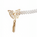 Close-up of a curtain tieback's gold butterfly set with crystals beside a double pearl bead chain