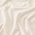 Close-up of cream velvet curtain fabric showing gentle folds and soft pile
