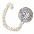 Close-up of a curtain tieback's round crystal centerpiece  in a pave setting beside a double pearl chain
