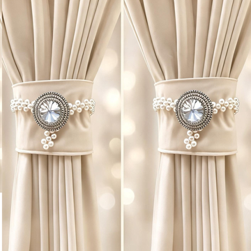 Two crystal and pearl curtain tiebacks holding cream curtain panels either side of a window