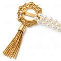 Gold medallion of an opalescent pearl curtain tieback showing the bar back connection and chain tassel