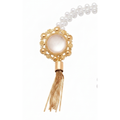 Close-up of a curtain tieback's opalescent stone set in a gold filigree medallion above a chain tassel