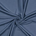 Slate blue plain velvet curtain fabric arranged in a swirl showing its smooth drape

