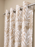 Beige floral curtain panel hanging from a steel rod on silver eyelets against a cream wall