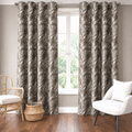 Brown floral curtains hung around a window in a neutral living room with a white armchair and wooden floor