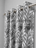 Grey floral curtain panel hanging from a steel rod on silver eyelets against a plain wall