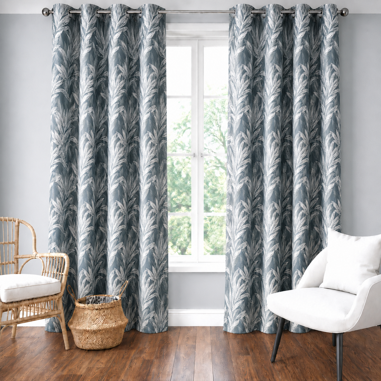 Grey floral curtains framing a sunlit window in a living room with a white armchair and wooden floor